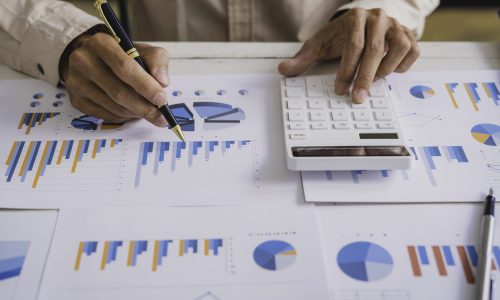 Businessmen hold graph pens and use a calculator for the company's improvement plan.