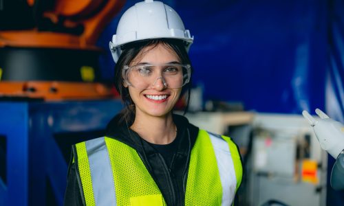 Female technician engineer using controller checking and operating automatic robotic machine at industrial factory, Worker working with robotic arms system in factory