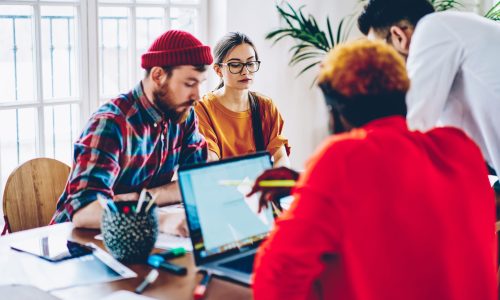 Skilled male and female freelancers have brainstorming meeting for discussing high tech and internet connection for web projecting via laptop device, young IT professionals collaborating at desktop